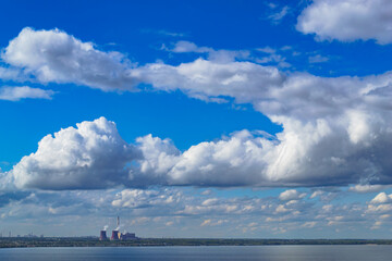 Industrial power plant by lake under blue sky