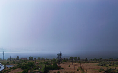 Rainstorm over lake and industrial cityscape
