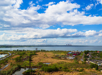Power plant by lake under bright beautiful clouds