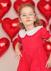 Little girl in red polka-dot dress poses with heart balloons.
Studio portrait captures Valentine theme and joyful emotion.
Bright background highlights childhood beauty and confidence.
