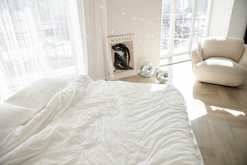 Bright Scandinavian bedroom with white bedding and sunlight.
Soft textures and wooden floor create modern minimalist design.
Art poster and disco balls add artistic cozy atmosphere