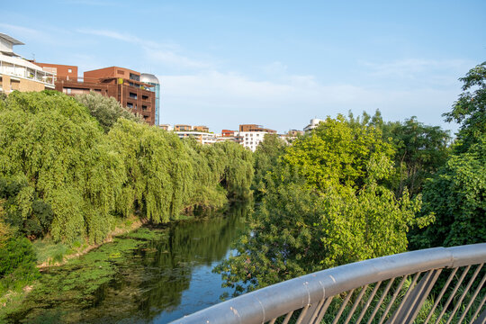 Scenic riverbank with urban greenery and residential buildings in Montpellier, reflecting sustainable city planning and connection between architecture and natural landscape