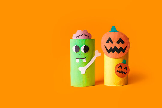 Halloween monsters from toilet paper roll tube, easy DIY handmade decorations idea. Paper toys zombie and vampire on yellow background. Kids creativity, easy eco craft, step by step, place for text