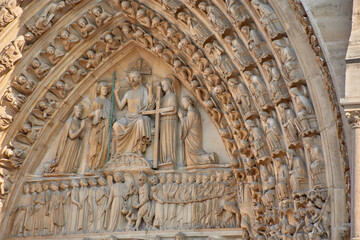 Close-up of religious sculptures on the facade of Notre Dame in Paris with stone-carved figures and Gothic architecture