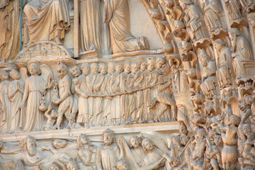 Close-up of religious sculptures on the facade of Notre Dame in Paris with stone-carved figures and Gothic architecture