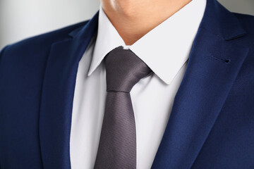 Man in suit with stylish necktie on grey background, closeup