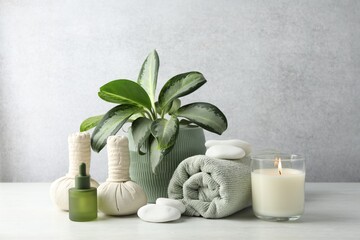 Beautiful spa composition with herbal bags and burning candle on white table