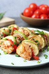 Tasty skewers with chicken, vegetables and green onion on grey table, closeup