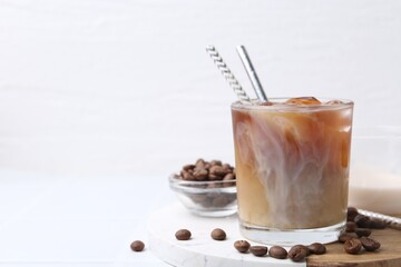 Tasty iced coffee with milk and beans on white table. Space for text