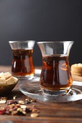 Traditional Turkish tea, brew, sugar and sweets on wooden table, closeup
