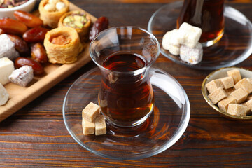 Traditional Turkish tea, brown sugar and sweets on wooden table, closeup