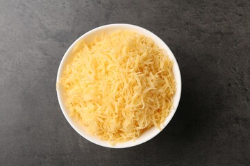 Grated cheese in bowl on grey table, top view