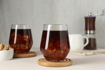 Tasty iced coffee and sugar on white table
