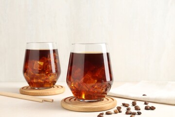 Tasty iced coffee and beans on white table