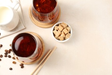 Tasty iced coffee, milk, sugar and beans on white table, flat lay. Space for text