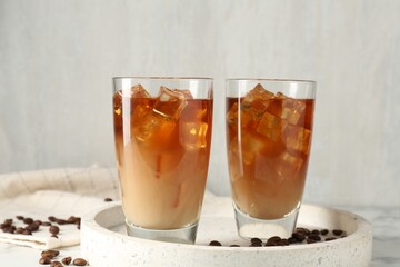 Tasty iced coffee with milk and beans on table