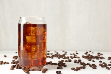 Tasty iced coffee and beans on white wooden table. Space for text