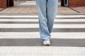 Person walking on crosswalk with casual clothing in urban setting during daytime