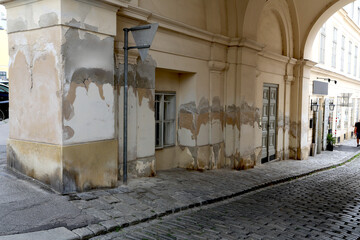 Traces d'humidité et auréoles sur un immeuble ancien dans une rue pavée © luzulee