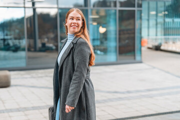 Fototapeta premium Business woman walking confidently in urban setting during daytime with modern architecture in the background