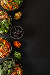 Fresh fruits and vegetables, frozen and placed in plates, on a dark backdrop, symbolizing the process of summer preparations for the colder months ahead