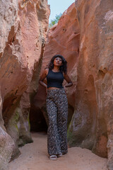 A woman wearing black pants and a black tank top is walking through a cave