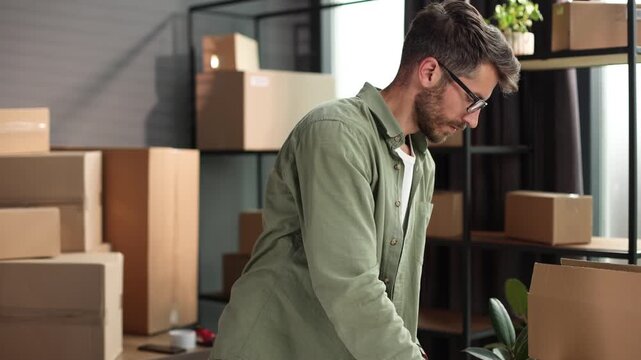 A man is standing in front of a pile of boxes, sorting through them