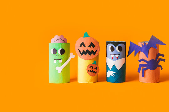 Halloween monsters from toilet paper roll tube, easy DIY handmade decorations idea. Paper toys zombie and vampire on yellow background. Kids creativity, easy eco craft, step by step, place for text