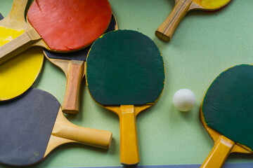 several colorful table tennis rackets and one white ball scattered on a green surface concept of...