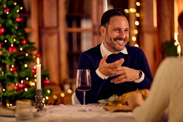 Smiling Man Enjoying Festive Christmas Dinner With Family, Wine, And Holiday Lights