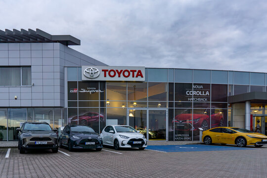 Toyota car dealership with new vehicle models outside the building, Corolla and Prius display on parking area