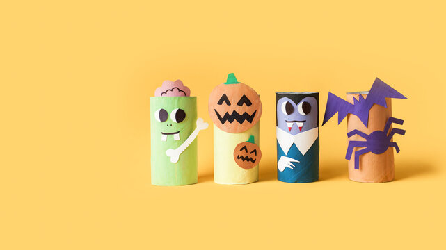 Halloween monsters from toilet paper roll tube, easy DIY handmade decorations idea. Paper toys zombie and vampire on yellow background. Kids creativity, easy eco craft, step by step, place for text
