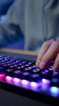 Computer keyboard with colorful lights and hands of a gamer streamer playing online video game
