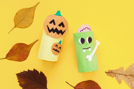 Halloween monsters from toilet paper roll tube, easy DIY handmade decorations idea. Paper toys zombie and vampire on yellow background. Kids creativity, easy eco craft, step by step, place for text