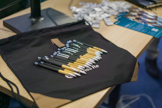 Bratislava, Slovakia, Europe - Oct 16, 2025: swiss re pens and swag on a black drawstring bag and table at a business conference concept of corporate event, sponsorship marketing, financial services
