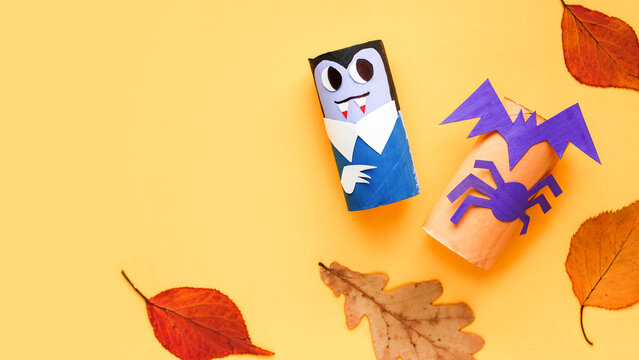 Halloween monsters from toilet paper roll tube, easy DIY handmade decorations idea. Paper toys zombie and vampire on yellow background. Kids creativity, easy eco craft, step by step, place for text