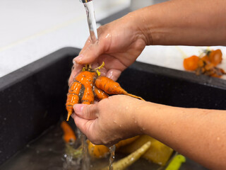 Washing fresh carrots in the kitchen