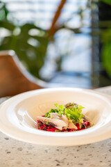 Gourmet fish salad with shredded beets and microgreens served in a white bowl on a restaurant table. Elegant plating, vibrant colors, fine dining atmosphere.