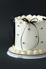 Delicate lambeth style birthday cake with white cream cheese frosting decorated with cream tracery and black happy birthday text on top. Black background