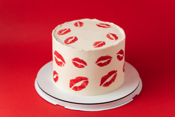 Beautiful birthday white cake decorated with red lips traces pattern. Happy Valentine's cake on the red marble background