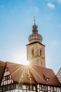 Kirchturm St. Martin in Forchheim bei Sonnenschein &ndash; historisches Fachwerkhaus mit Sonnenstern und blauem Himmel