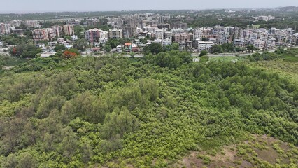 Obraz premium High-resolution aerial photograph showcasing a vibrant coastal city in India, bordered by dense green mangroves and a wide river leading to the sea