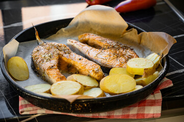 Baked salmon steaks with potatoes on a baking tray. Freshly cooked meal showing golden roasted potatoes and perfectly cooked salmon, ideal for healthy cuisine and culinary presentation.