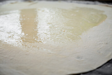 Spreading butter onto dough for puff pastry preparation. Close-up of a baking process demonstrating traditional pastry technique and culinary skill.