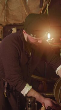 Barkeeper pours ale from barrel and turns to counter at inn. Plump bartender in medieval suit looks with servile smile at guest in tavern. Fantasy world