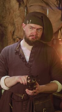 Bearded keeper holds dry herbs for potion in store. Serious seller hides dangerous ingredients in metal container in medieval tavern. Magical shop