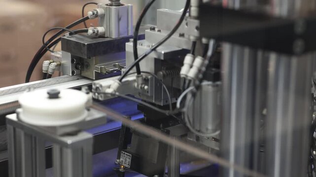 Close-up view of advanced automated machinery operating in an industrial environment with visible wiring and mechanical components. No identifiable branding or logos visible