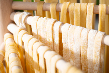 Homemade noodles hanging on wooden dryer rack closeup low angle view