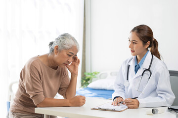 Fototapeta premium Young doctor providing medical consultation to concerned senior woman in a hospital or clinic setting, discussing health issues
