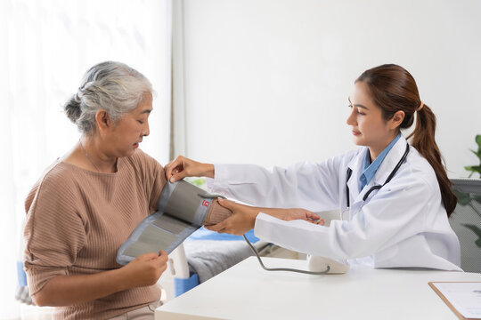 Young Asian doctor checking blood pressure of an elderly Asian woman during a routine health check up in a clinic